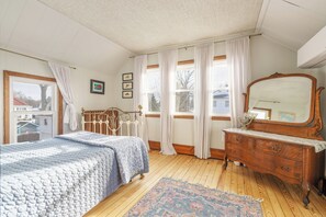 A bedroom with a bed, dresser, and large windows.