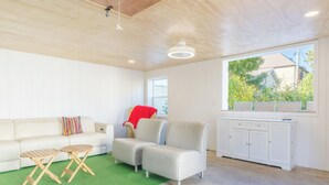 A modern living room with a white sofa, two armchairs, a green artificial turf area, and a white cabinet.
