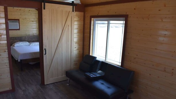 Ein Zimmer in einer Holzhütte mit einem Bett, einer Couch und einem Fenster.