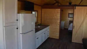 Eine kleine Küche mit weißen Schränken, einem Kühlschrank und einem Spülbecken.