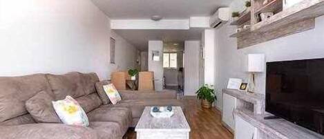A living room with a sofa, a coffee table, and a TV.