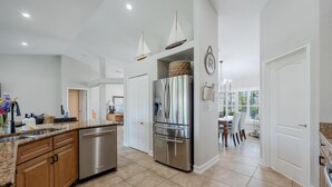 A modern kitchen with stainless steel appliances, wooden cabinets, and a granite countertop. - LAKEVIEW!, Heated Pool and Spa -Villa Lakeside Escape - Roelens Vacations (Cape Coral)