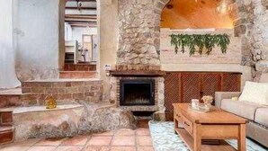 A rustic interior with a stone fireplace, a wooden coffee table, and a sofa. - Altea Suite Vault by Vero (Altea)
