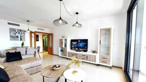 Ein modernes Wohnzimmer mit einem Ecksofa, einem Couchtisch, einem Fernseher und einem Glaskabinet.