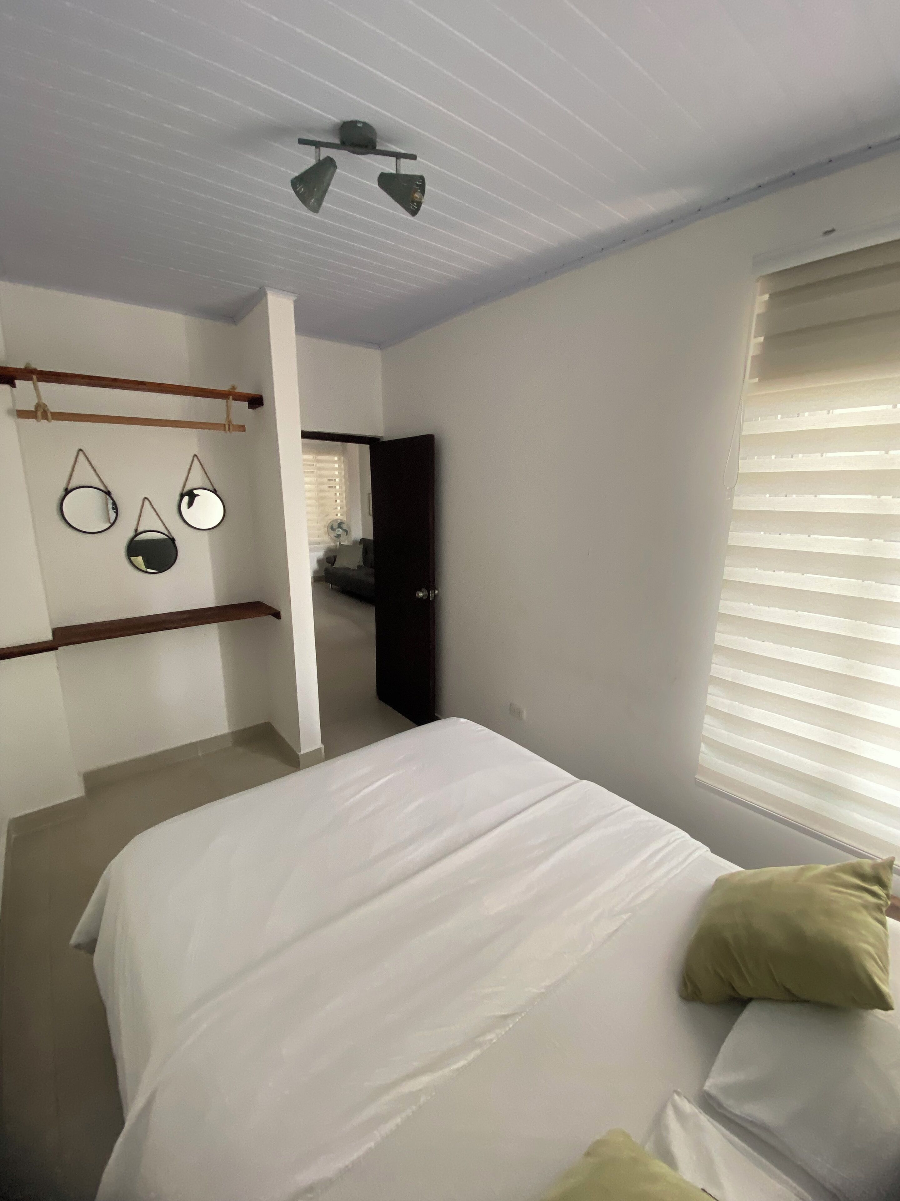 A bedroom with a bed, a ceiling fan, and a window with blinds.