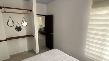 A bedroom with a bed, a ceiling fan, and a window with blinds.