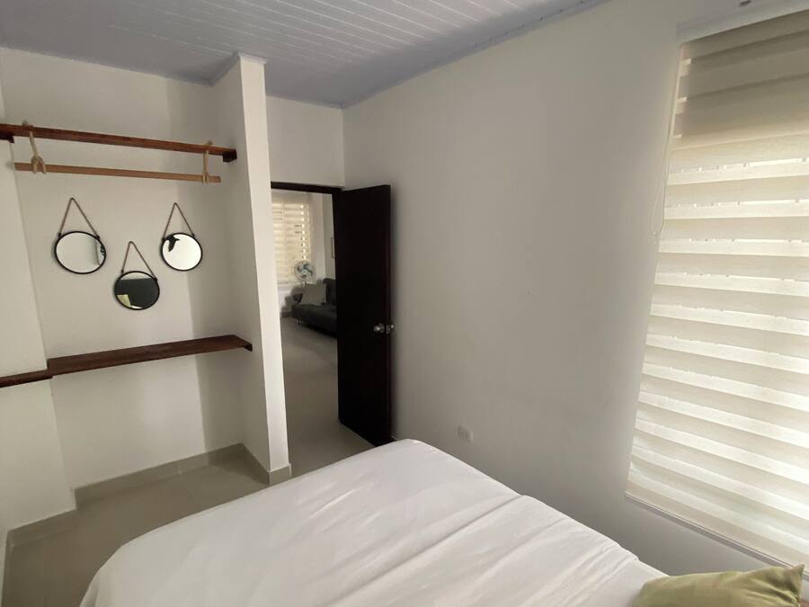 A bedroom with a bed, a ceiling fan, and a window with blinds.