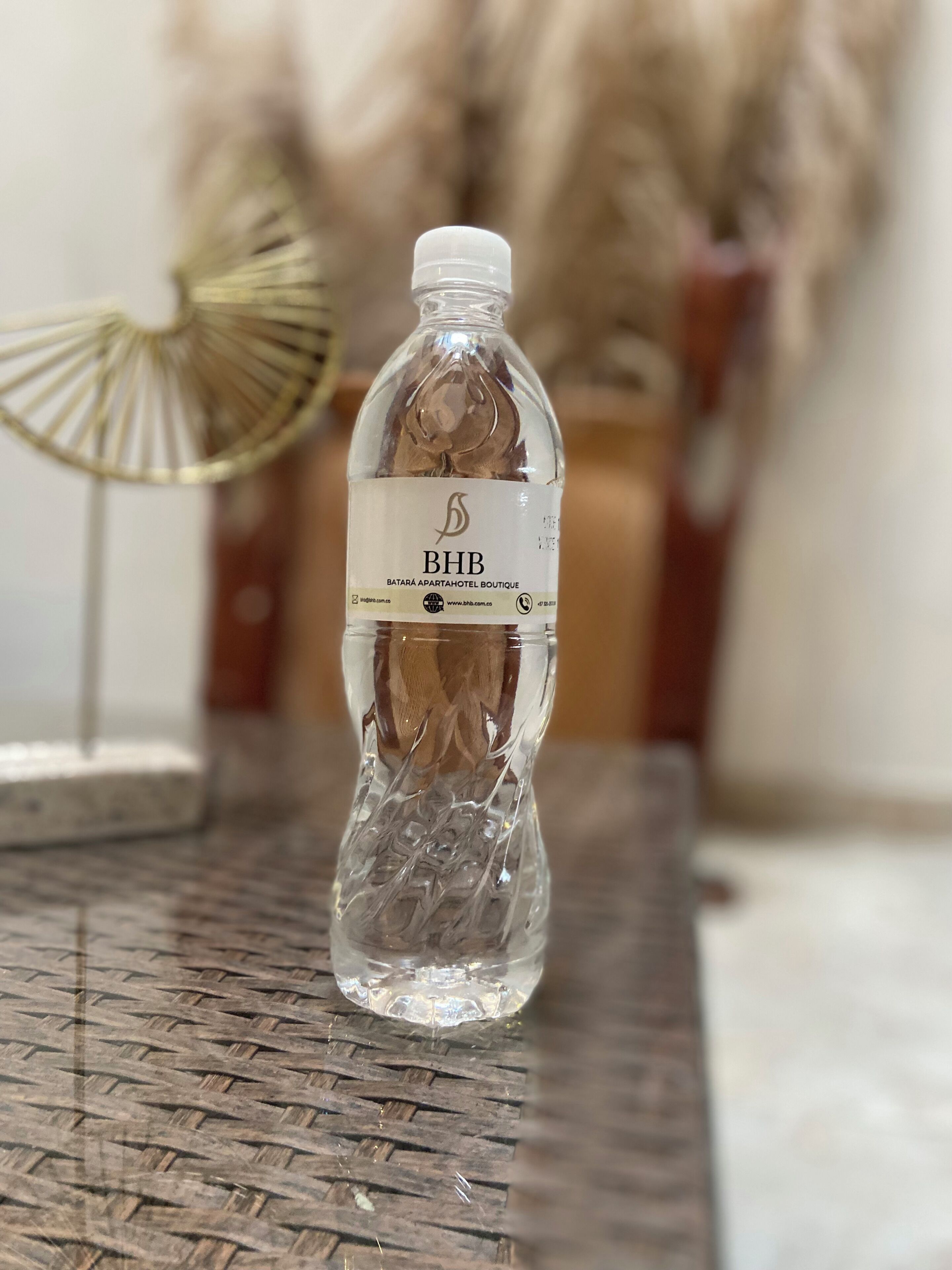 A clear plastic water bottle with a label on a woven table.