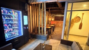 Un espace de détente moderne équipé d’un distributeur automatique, de sièges et offrant une vue sur l’extérieur.