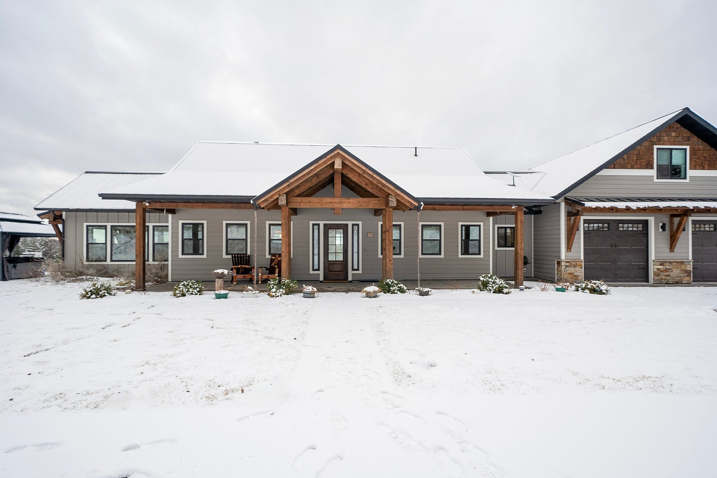 Ein zweistöckiges Haus mit Veranda, Garage und einem schnee bedeckten Vorgarten.