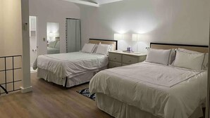 A hotel room with two beds, a bedside table with lamps, a mirror, and a wardrobe.