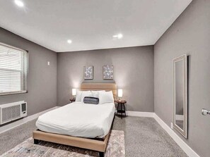 A bedroom with a bed, bedside lamps, a radiator, and a framed picture on the wall.