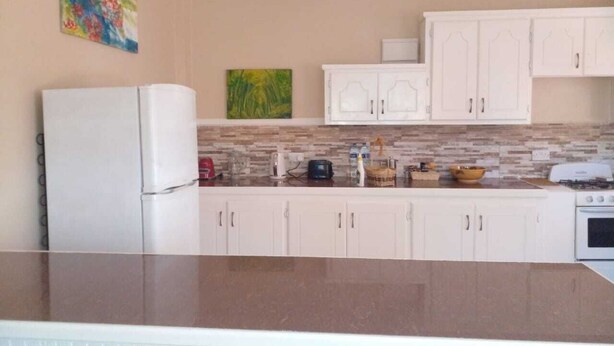 A kitchen with white cabinets, a granite countertop, a refrigerator, a stove, and a microwave.