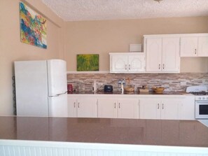 A kitchen with white cabinets, a granite countertop, a refrigerator, a stove, and a microwave.