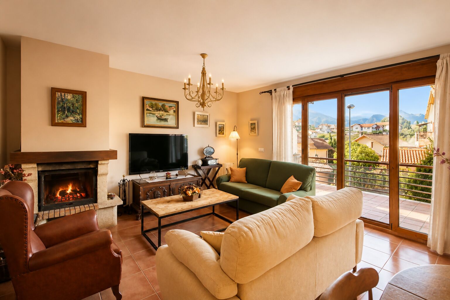 A living room with a fireplace, a green sofa, a leather armchair, a television, and a view of a mountainous landscape through large windows.