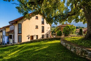 Un bâtiment traditionnel avec un mur en pierre, un petit jardin et un arbre.