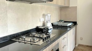 A modern kitchen with wooden cabinets, a gas stove, a coffee maker, and a toaster. - Appartement Sympa (Marrakech)