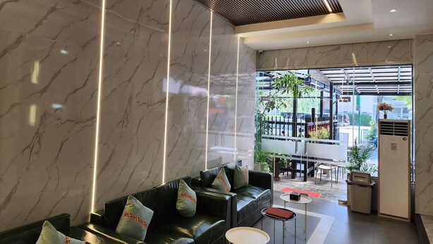A modern lobby with a marble wall, a black leather sofa, and a glass door leading outside.