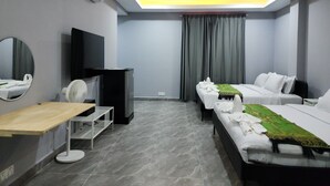 A hotel room with two beds, a desk, a mirror, a TV, and an air conditioning unit.