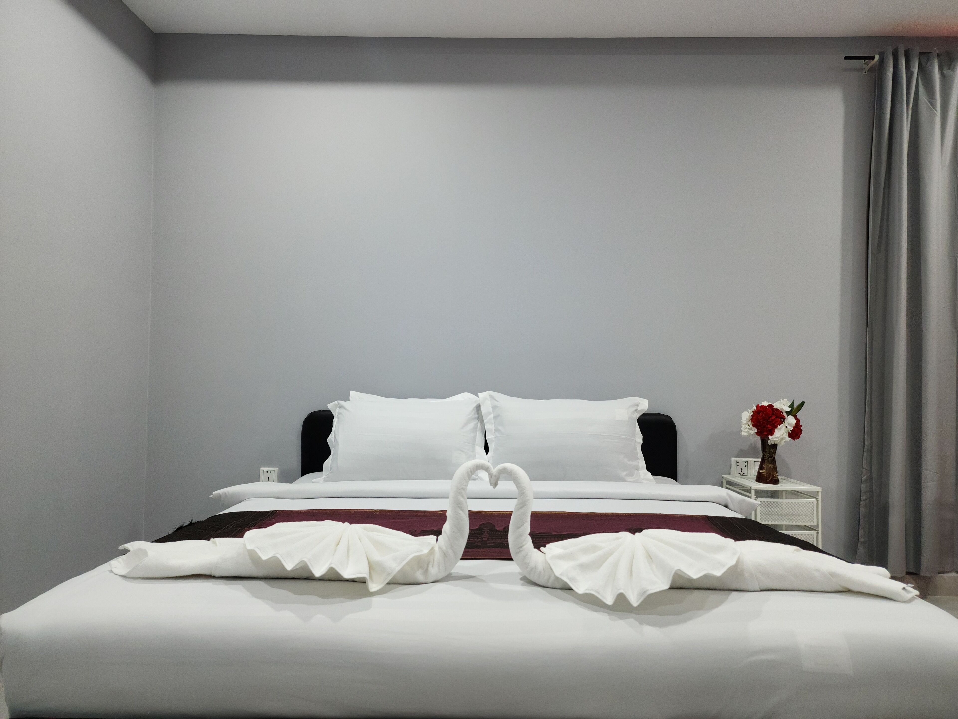 A neatly made bed with white linens and a decorative swan design on the pillows.