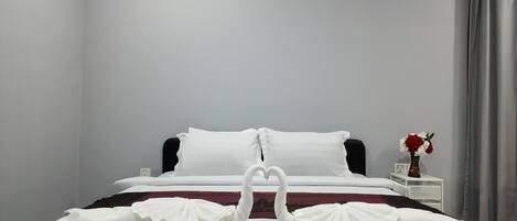 A neatly made bed with white linens and a decorative swan design on the pillows.