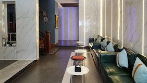 A modern lobby with marble walls, a leather sofa, and a staircase.