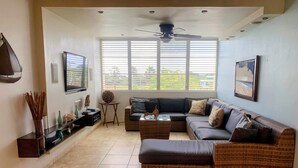 A modern living room with a sectional sofa, a coffee table, and a ceiling fan. - Spacious 3 bedrooms penthouse, near Combate Beach: Pools, Fun & Amazing Sunsets (Cabo Rojo)