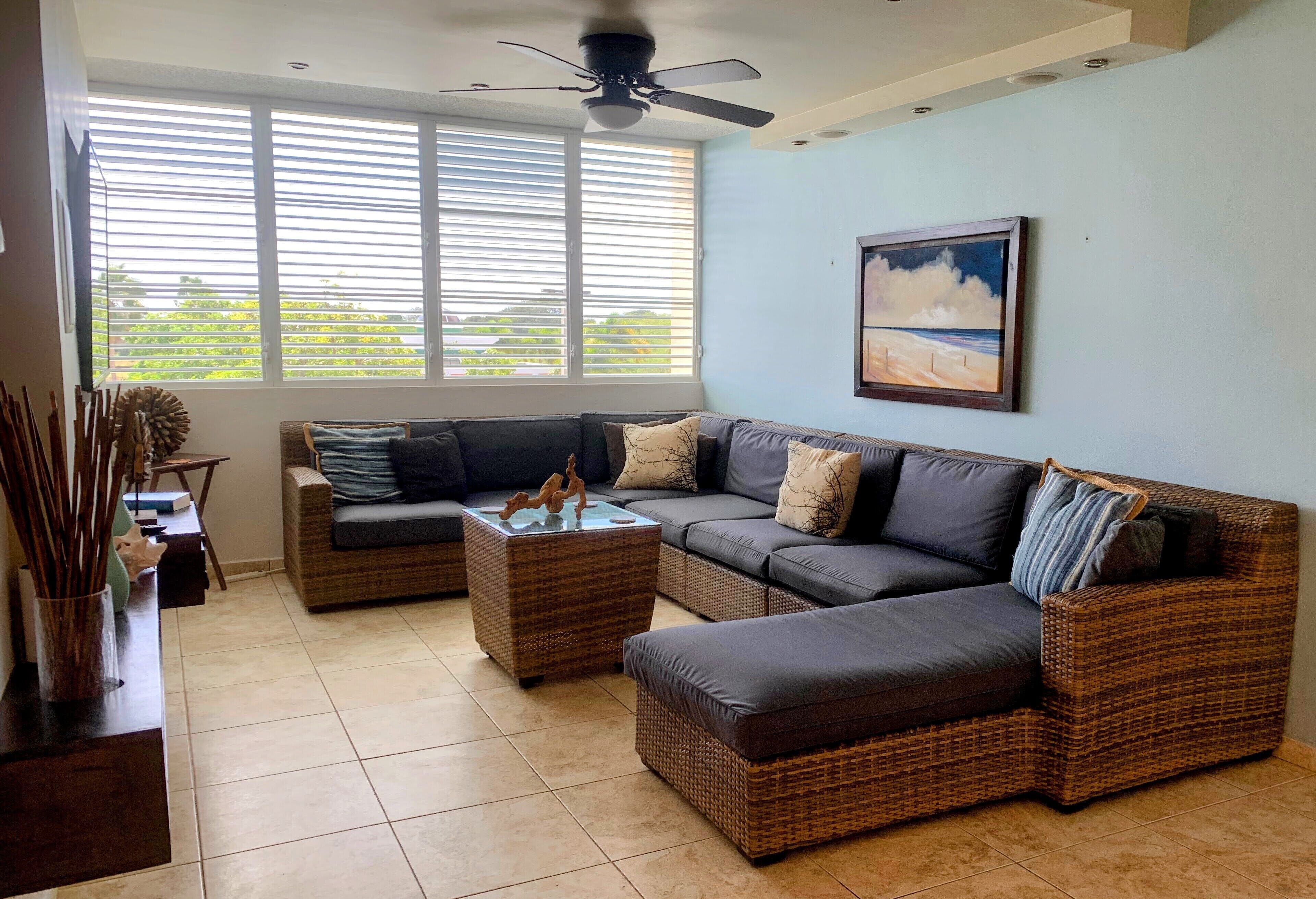 A living room with a sectional sofa, two side tables, and a ceiling fan.