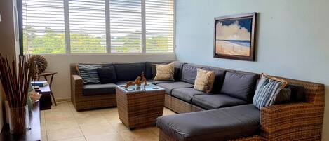 A living room with a sectional sofa, two side tables, and a ceiling fan.
