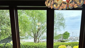 A wooden table with a metal tiered tray in a room with large windows overlooking a green landscape and a marina. - "The Lake House" With Spectacular Views!!! Steps to Beach!! (Port Elgin)