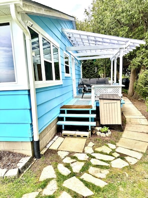 A blue house with a porch, a small garden, and a stone pathway.