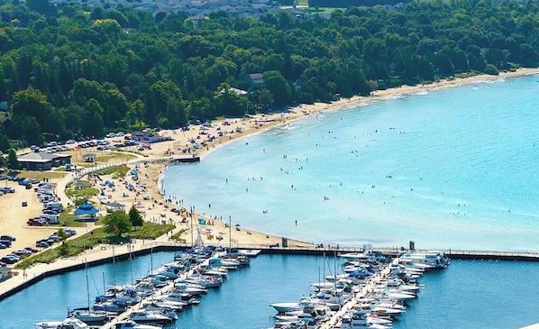 A coastal area with a marina, beach, and surrounding greenery.