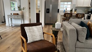 Een moderne woonkamer met een bruine fauteuil, een grijze bank en een klein, rond tafeltje met een zakdoos.