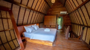 A wooden room with a bed, a wardrobe, and a staircase. - RaCottage Mandalika (Kuta)