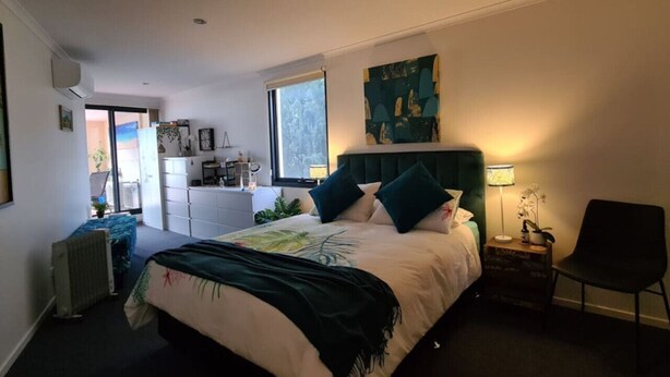 Een slaapkamer met een bed, een raam, een bureau en een stoel.
