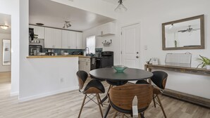 A modern kitchen with white cabinets, a round dining table, and black chairs. - Bay Breeze Bungalow (St. Augustine)