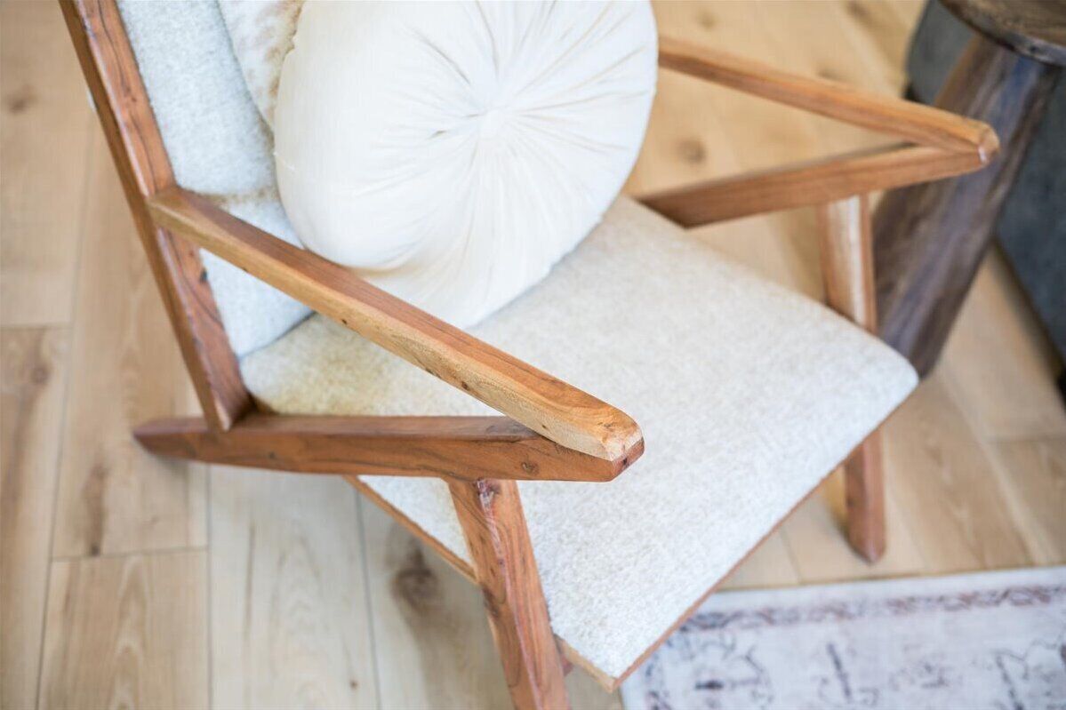 A wooden chair with a white cushion and a textured seat.