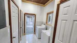A laundry room with a washing machine and dryer, a window, and a door leading to an outdoor area.