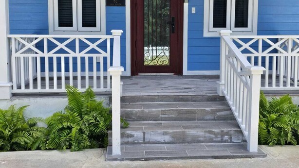 A blue house with a dark red door, white shutters, and a white porch railing.