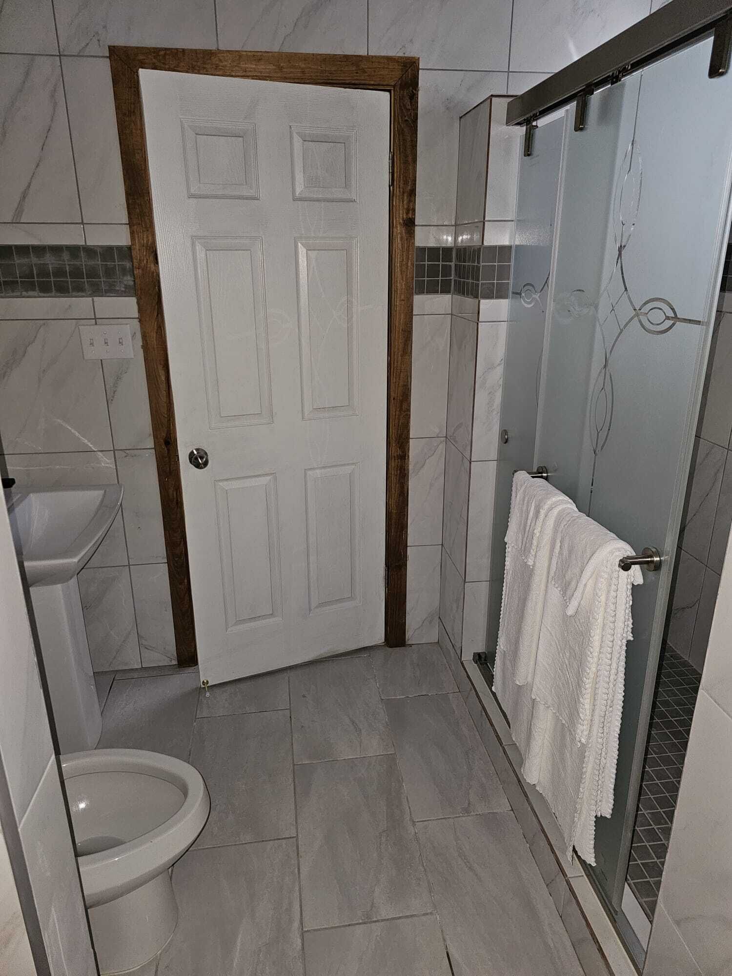 Een badkamer met toilet, wastafel en douchecabine.
