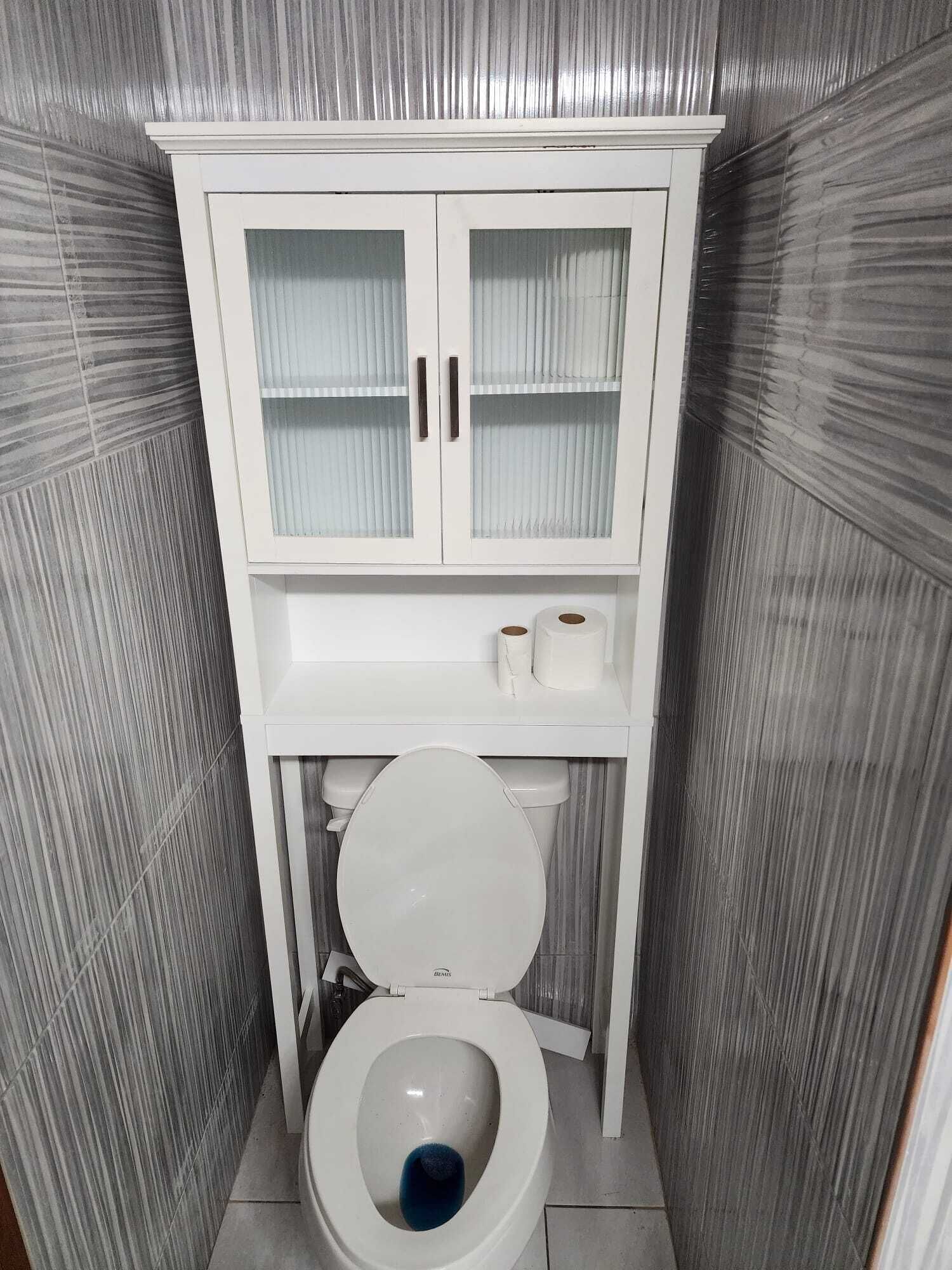 A bathroom with a white toilet, a cabinet with glass doors, and a toilet paper holder.