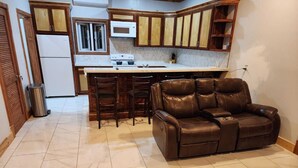 A kitchen with a built-in microwave, a stove, and wooden cabinets. There is a brown leather sofa in the living area.
