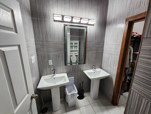 A bathroom with two sinks, a mirror, and a toilet.