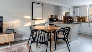 Una cocina moderna con armarios blancos, una mesa de comedor de madera y sillas negras.