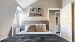 Un dormitorio con una cama grande, cabecera y una ventana.