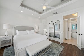A spacious bedroom with a large bed, bedside tables, a mirror, and a walk-in closet. - The Hummingbird - Lakefront Vacation Home with Private Pool & Water Views (Destin)