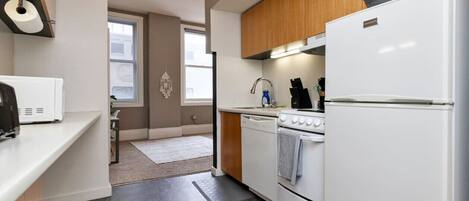 Una cocina moderna con electrodomésticos blancos, armarios de madera y un ventanal grande.