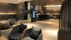 A modern lobby with a reception desk, seating area, and a large digital screen.