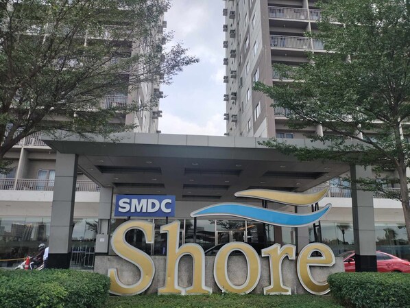 A building with a sign reading "SMDC Shore" and a large "Shore" sign in front. - Shore Residences Stays by PBYY (Pasay)