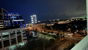 A nighttime cityscape with illuminated buildings and a busy road.